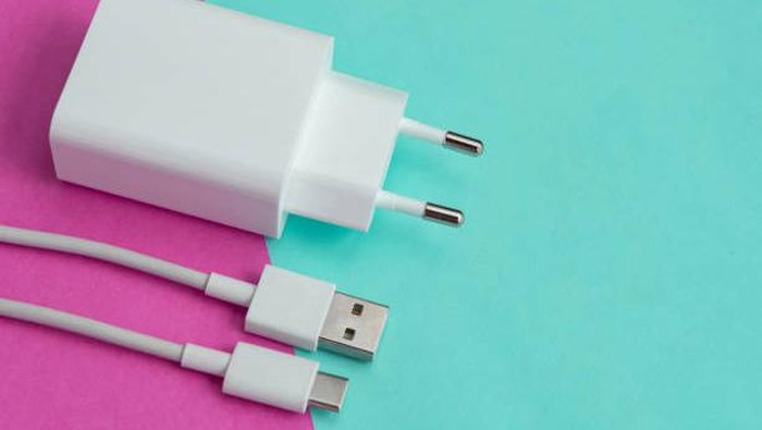 Charger and USB cable type C over pink and blue background