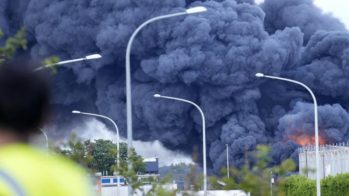A firefighter, right, works on a ladder truck as a fire rages on the roof of a commercial building at Brussels cargo airport in Brussels, Thursday, June 13, 2024. Firefighters from several municipalities were fighting the fire into the afternoon, no injuries were yet reported. (AP Photo/Virginia Mayo)