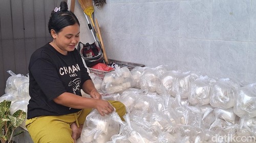 Zumaroh sedang membungkus tahu di teras kos-kosannya.