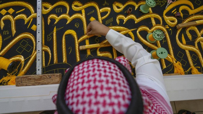 Melihat Penyulaman Kiswah Ka'bah di Makkah A Saudi man embroiders Islamic calligraphy, using either pure silver threads or silver threads plated with gold, during the final stages in the preparation of a drape, or Kiswa, that covers the Kaaba, a cube-shaped structure at the heart the Grand Mosque, at the Kiswa factory in Mecca, Saudi Arabia, Thursday, June 13, 2024. (AP Photo/Rafiq Maqbool)