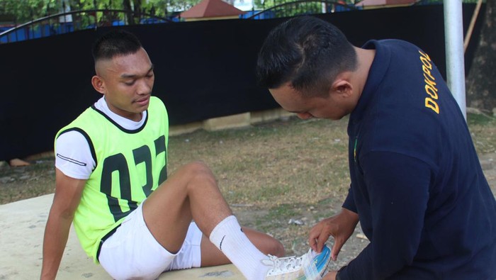 Petugas membantu melakban sepatu koyak Ayat Suci, salah satu peserta seleksi tes Tamtama Pori di Aceh. (dok Polda Aceh)