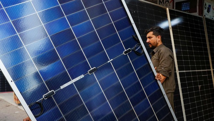 Warga Pakistan Beralih ke Panel Surya gegara Mati Listrik 14 Jam Sehari A worker loads solar panels on a vehicle, outside a shop at a market selling electronic items in Karachi, Pakistan June 11, 2024. REUTERS/Akhtar Soomro