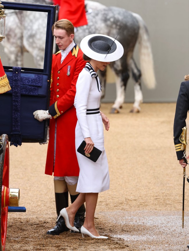 Kate kemudian menyempurnakan gayanya dengan topi unik berbentuk piring pipih karya Philip Treacy, clutch Mulberry, dan sepasang heels putih Jimmy Choo. Tidak ketinggalan beberapa perhiasan regalia yang semakin mempertegas aura bangsawan. (Foto: Mike Marsland/WireImage)
