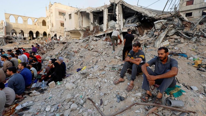 Potret Pilu Warga Gaza Salat Idul Adha di Reruntuhan Masjid Palestinians hold Eid al-Adha prayers by the ruins of the Al-Rahma mosque destroyed by Israeli air strikes, amid the Israel-Hamas conflict, in Khan Younis, in the southern Gaza Strip, June 16, 2024. REUTERS/Mohammed Salem