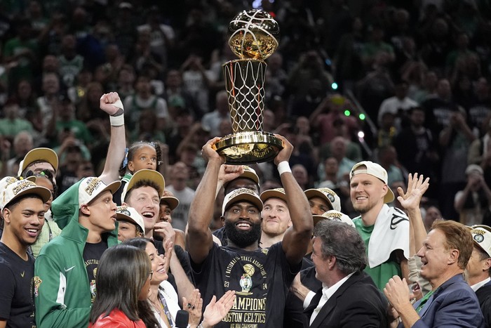 Boston Celtics guard Jaylen Brown, center, holds up the Larry OBrien Championship Trophy as he celebrates with the team after they won the NBA basketball championship with a Game 5 victory over the Dallas Mavericks, Monday, June 17, 2024, in Boston. (AP Photo/Charles Krupa)