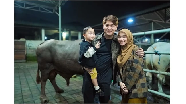 Pasangan selebritas Lesti Kejora dan Rizky Billar juga turut meramaikan Idul Adha tahun ini dengan berkurban sapi jumbo. Bersama sang putra, mereka berpose dalam balutan serba gelap di depan sapi yang mereka kurbankan. (Foto: Instagram)