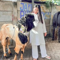 Via Vallen juga mengandalkan busana serba putih dalam padanan tunik dan celana panjang. Ia mengunggah momen dirinya membelai kambing kurbannya. (Foto: Instagram)