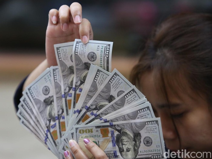 Karyawan menunjukan uang dolar Amerika Serikat (AS) dan Rupiah di salah satu gerai penukaran mata uang asing di Jakarta, Selasa (18/6/2024).