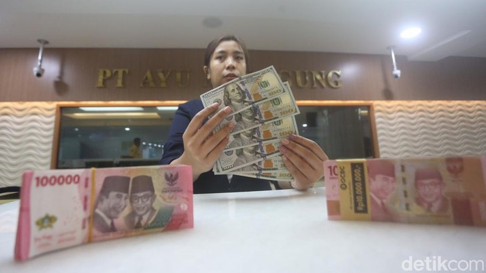 Karyawan menunjukan uang dolar Amerika Serikat (AS) dan Rupiah di salah satu gerai penukaran mata uang asing di Jakarta, Selasa (18/6/2024).