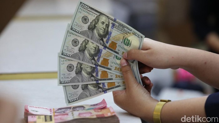 Karyawan menunjukan uang dolar Amerika Serikat (AS) dan Rupiah di salah satu gerai penukaran mata uang asing di Jakarta, Selasa (18/6/2024).