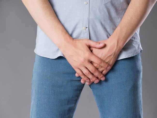 Pain in prostate, man suffering from prostatitis or from a venereal disease, studio shot on gray background