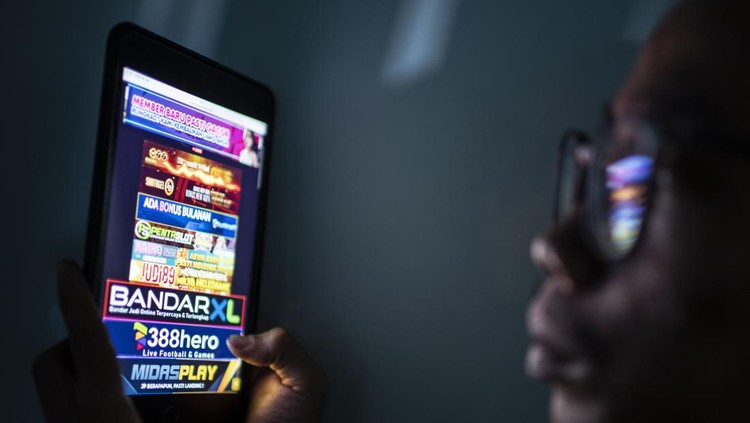 Refleksi warga saat melihat iklan judi online melalui gawainya di Jakarta, Rabu (19/6/2024). Kementerian Komunikasi dan Informatika (Kominfo) telah memblokir sebanyak 2,1 juta situs web untuk memberantas perjudian dalam jaringan atau online di Indonesia. ANTARA FOTO/Aprillio Akbar/rwa.
