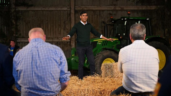 Momen Rishi Sunak Berkampanye di Pertanian British Prime Minister Rishi Sunak speaks to farmers as he campaigns on a farm near Barnstaple in North Devon, Britain, June 18, 2024. Leon Neal/Pool via REUTERS