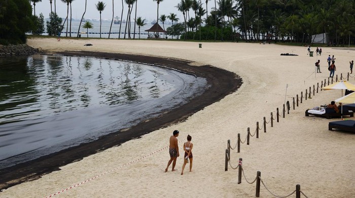 Pantai Sentosa Singapura Ditutup gegara Tumpahan Minyak, Begini Kondisinya People walk next to an oil slick at Tanjong Beach on Sentosa, Singapore June 15, 2024. REUTERS/Edgar Su