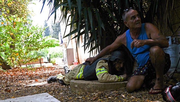 An Israeli firefighter and another Israeli man take cover as a siren for incoming rockets from Lebanon into Israel goes off, amid cross-border hostilities between Hezbollah and Israeli forces, in Kiryat Shmona, northern Israel June 19, 2024. REUTERS/Ayal Margolin ISRAEL OUT. NO COMMERCIAL OR EDITORIAL SALES IN ISRAEL