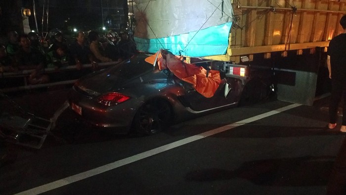 Sedan Porsche menabrak truk mengangkut 35 ton tepung sagu di Tol Dalam Kota Jakarta. Lebih dari setengah panjang sedan tersebut tersangkut di kolong truk. (dok Istimewa)