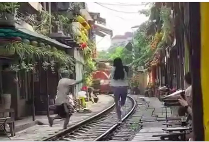Turis berpose di rel kereta Hanoi