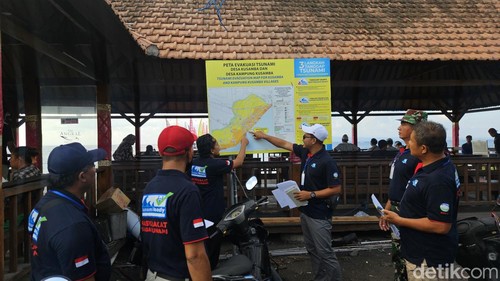 Peserta sekolah lapang gempa bumi 2024 Klungkung menunjuk tanda zona bahaya tsunami yang dipasang di Pelabuhan Kampung Kusamba, Jumat (21/6/2024). (foto : Putu Krista/detikBali).