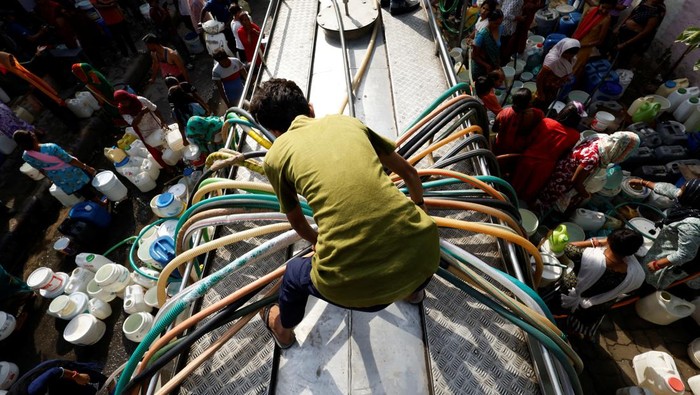 Bingkai Sepekan: Panas Memanggang, Badai Menerjang Residents use pipes to fill their containers with drinking water from a water tanker during a hot day in New Delhi, India, June 13, 2024. REUTERS/Priyanshu Singh