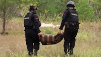 Dua polisi membawa mortir itu yang sudah siap untuk diledakkan. Mereka menuju titik yang dirasa aman untuk lokasi peledakan.