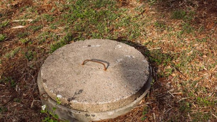 Septic tank lid cover made of concrete. Domestic sewage concept for environmental issues, home owner problems, hygiene, or waste management for home owners.