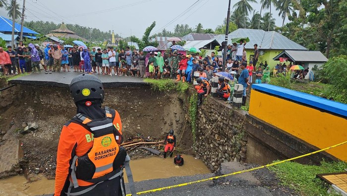 Seorang pemotor bernama Maskun Mantu (38) terjatuh di Jalan Trans Sulawesi di Kabupaten Bone Bolango, Gorontalo yang putus diterjang banjir.