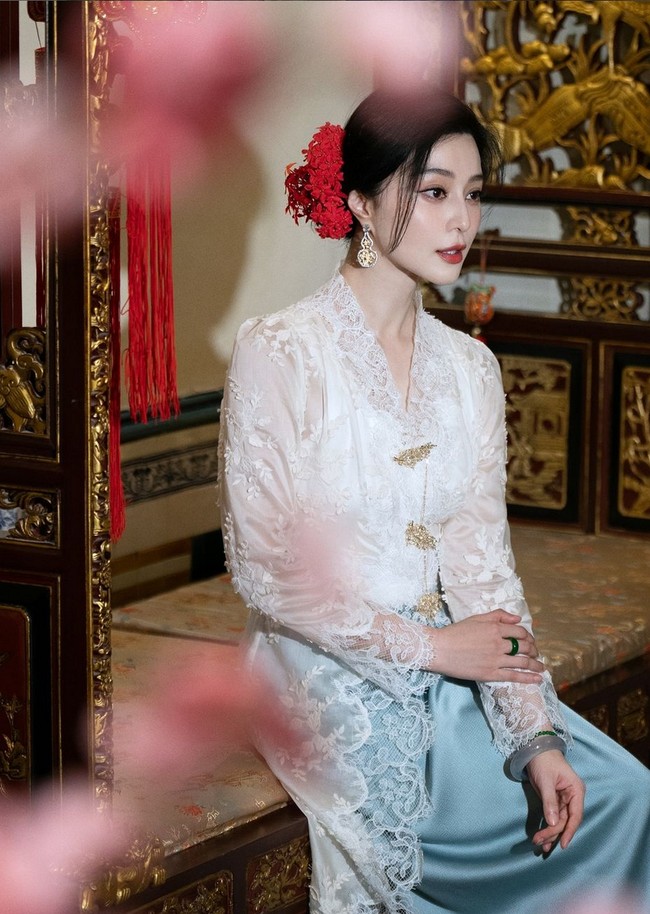 Penampilannya semakin anggun dengan sanggul menyamping yang dihias aksen bunga di rambut. Tak lupa lipstik merah yang jadi ciri khas riasannya. Foto: Instagram/@bingbing_fan