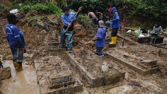 Sejumlah petugas membersihkan makam yang tertimbun tanah longsor di Taman Pemakaman Umum (TPU) Sei Panas, Batam, Kepulauan Riau, Sabtu (22/6/2024). Areal perkuburan di TPU tersebut longsor akibat intensitas hujan tinggi sejak sepekan terakhir yang menyebabkan sekitar 30 makam tertimbun tanah dan rusak. ANTARA FOTO/Teguh Prihatna/YU