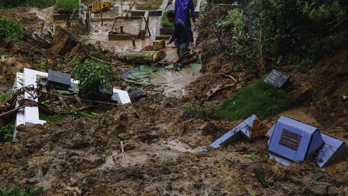Sejumlah petugas membersihkan makam yang tertimbun tanah longsor di Taman Pemakaman Umum (TPU) Sei Panas, Batam, Kepulauan Riau, Sabtu (22/6/2024). Areal perkuburan di TPU tersebut longsor akibat intensitas hujan tinggi sejak sepekan terakhir yang menyebabkan sekitar 30 makam tertimbun tanah dan rusak. ANTARA FOTO/Teguh Prihatna/YU