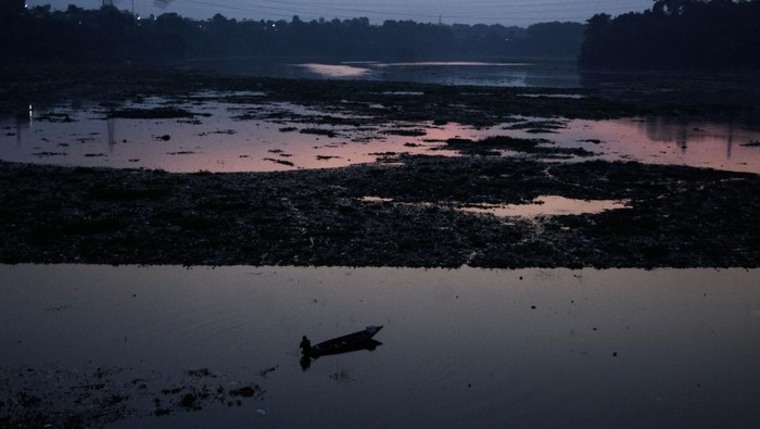 Warga menaiki perahu di dekat tumpukan sampah yang telah dijaring di aliran Sungai Citarum, Kabupaten Bandung Barat, Jawa Barat, Jumat (21/6/2024). Pemerintah Jawa Barat menerapkan jaring penyekat sampah di sejumlah titik dari hulu hingga hilir di aliran Sungai Citarum sebagai salah satu pilihan dalam mengatasi dan mengantisipasi sampah yang terbawa arus ataupun mengendap di aliran sungai. ANTARA FOTO/Novrian Arbi/aww.