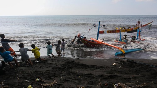 Prajurit TNI AL membantu nelayan menarik perahu yang karam akibat terhantam ombak di Pantai Cemara Banyuwangi, Jawa Timur, Sabtu (22/6/2024). Untuk menghindari resiko tinggi dalam pelayaran, Badan Meteorologi, Klimatologi dan Geofisika (BMKG) Banyuwangi mengimbau agar masyarakat yang akan melakukan aktivitas melaut agar mempertimbangkan kondisi cuaca karena gelombang setinggi 1,25 meter hingga 2,5 meter berpeluang terjadi di Selat Bali bagian Selatan, Selat Badung hingga laut Sumbawa. ANTARA FOTO/Budi Candra Setya/nz