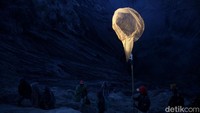 Beberapa masyarakat Suku Tengger berada di lereng kawah Gunung Bromo untuk menangkap sesaji yang dilarung dengan jaring.