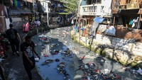 Warga melintas di pinggir aliran Sungai Ciliwung Kecil di kawasan Kebon Kacang, Tanah Abang, Jakarta, Minggu (23/6/2024).