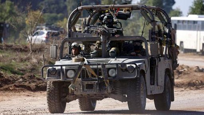 Israeli troops ride a military jeep along the border with the Gaza Strip on December 3, 2023, after battles resumed between Israel and Hamas militants, as clashes continue between Israel and Hamas militants on December 3, 2023. Israel carried out deadly bombardments in Gaza on December 3 as international calls mounted for greater protection of civilians and the renewal of an expired truce with Palestinian militant group Hamas. (Photo by JACK GUEZ / AFP)