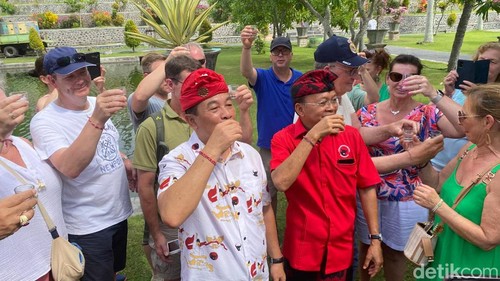 Ketua DPD PDIP Bali Wayan Koster mengajak para wisatawan mencoba arak Bali di Taman Soekasada Ujung, Karangasem, Minggu (23/6/2024) (I Wayan Selamat Juniasa/detikBali)