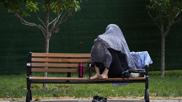 Warga Beijing menggunakan pelindung wajah saat beraktivitas diluar rumah di tengah cuaca panas ekstrem. (AP Photo/Andy Wong)