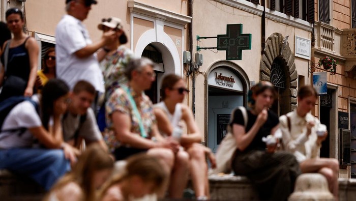 Dea from Georgia uses a fan to cool off as she walks near the Colosseum amid a heatwave in Rome, Italy, June 20, 2024. REUTERS/Guglielmo Mangiapane