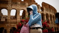 Ada juga wisatawan yang menggunakan pakaian yang serba tertutup agar terlindung dari panas. REUTERS/Guglielmo Mangiapane