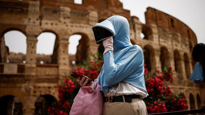 Dea from Georgia uses a fan to cool off as she walks near the Colosseum amid a heatwave in Rome, Italy, June 20, 2024. REUTERS/Guglielmo Mangiapane