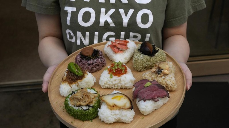 Tourists from Australia eat onigiri, rice balls, at a Taro Tokyo Onigiri shop in Tokyo, on June 5, 2024. The word 