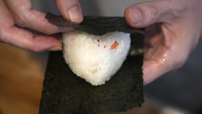 Kelezatan Onigiri Jepang yang Kini Masuk Kamus Bahasa Inggris Oxford Yosuke Miura wraps seaweed around a rice ball at Onigiri Asakusa Yadoroku, Tokyo's oldest onigiri restaurant, on June 3, 2024, in Tokyo. The word