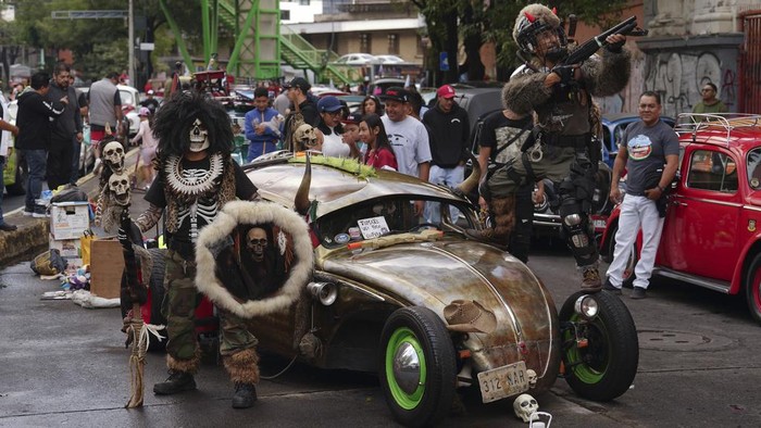 People walk past vintage Volkswagen Beetles, known in Mexico as 