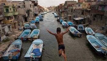 Karya Mohamed Mahdy, raih Silver di kategori Photojournalism. Seorang anak laki-laki melompat dari jembatan ke kanal desa Nelapan El-Max, Alexandria, Mesir. Sebelum pembongkaran, setiap nelayan memiliki perahu dan peralatannya diparkir di depan rumahnya. Penduduk biasa menyebut kanal ini Venesia Timur Tengah, karena menyerupai keindahan dan getaran Venesia Italia. Foto: 1839 Awards