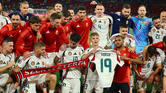Soccer Football - Euro 2024 - Group A - Scotland v Hungary - Stuttgart Arena, Stuttgart, Germany - June 23, 2024 Hungary players celebrate after the match and hold up a shirt with Barnabas Vargas name after he was stretchered off during the match REUTERS/Leonhard Simon