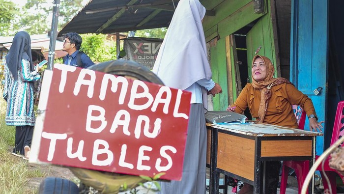 Calon Wali Murid Tetap Daftar PPDB di SDN 212 Kota Jambi yang Bersengketa Guru melayani calon wali murid saat pendaftaran Penerimaan Peserta Didik Baru (PPDB) Tahun Pelajaran 2024/2025 di depan SDN 212 Kota Jambi yang masih bersengketa di Jambi, Senin (25/6/2024). PPDB di sekolah yang pintu masuknya masih ditutup oleh pemilik lahan itu terpaksa dilakukan di luar sekolah akibat belum adanya kepastian penempatan kembali bangunan sekolah yang sedang berkonflik, sementara aktivitas belajar mengajar di sekolah tersebut masih dialihkan ke sekolah lain sejak satu semester terakhir. ANTARA FOTO/Wahdi Septiawan/rwa.