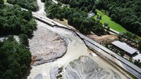 Tampak sebuah jalan raya rusak parah akibat diterjang banjir bandang.