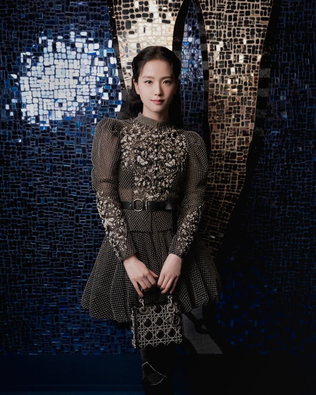 Jisoo BLACKPINK tampil bergaya demure fashion mengenakan mini dress dari koleksi Dior. Gaun hitam dengan kerah tinggi ini berhias payet dan mutiara yang memberi kesan glamor sekaligus elegan. Foto: dok. Twitter @NEWSJISOO