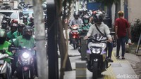 Beberapa pemotor menerobos trotoar untuk menembus kepadatan arus kendaraan.  