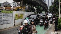 Para pengendara melintasi proyek gorong-gorong yang memotong jalan di Jalan Satrio, Setiabudi, Jakarta Selatan, Selasa (25/6/2024).