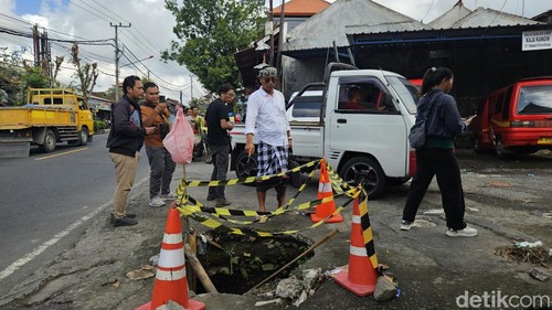 Kaling Samplangan I Wayan Gde Redhana tunjukkan lubang menganga yang mengakibatkan banyak pengendara kecelakaan, Rabu (26/6/2024). (I Putu Budikrista Artawan/detikBali)